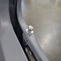 Close-up of a silver metallic mounting bolt or rivet attached to a curved gray metal frame, with a concrete floor visible in the background.