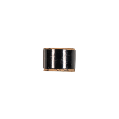 A small cylindrical black object with a metallic gold-toned top and bottom rim, centered on a plain white background.