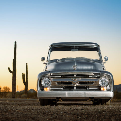 Vintage truck in a desert landscape with cacti and a sunset sky