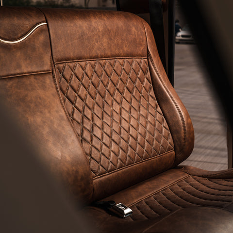 Brown leather car seat with diamond pattern stitching in a vehicle interior.