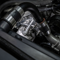 Close-up of a truck engine bay featuring Vibrom branded stainless steel and black silicone intake hoses connected to a silver engine component.