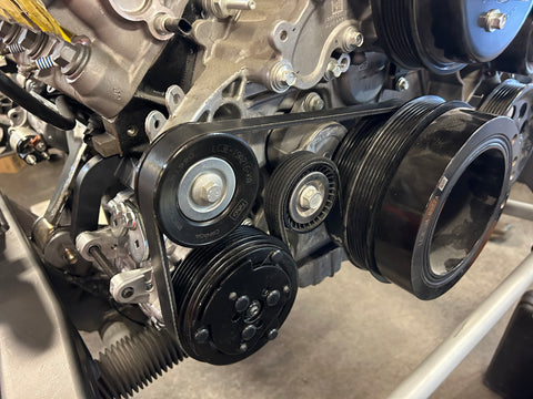 Close-up of an engine belt system with pulleys.