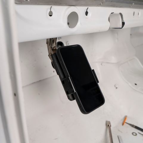 Under-dash phone holder in open position demonstrating single-hand slide operation for quick phone access